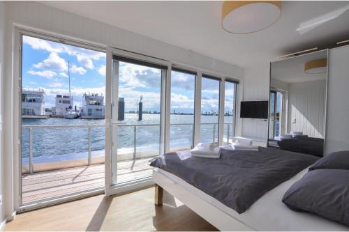 a bedroom with a large window with a view of the water at Schwimmendes Haus Haithabu in Olpenitz
