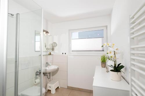a white bathroom with a sink and a shower at Schwimmendes Haus Ankerlicht in Olpenitz