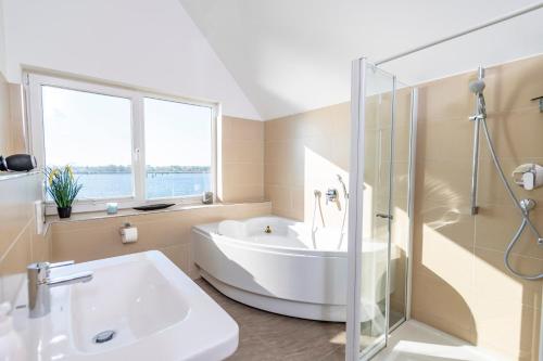 ein Bad mit einer Badewanne, einem Waschbecken und einer Dusche in der Unterkunft Hafenkante in Olpenitz