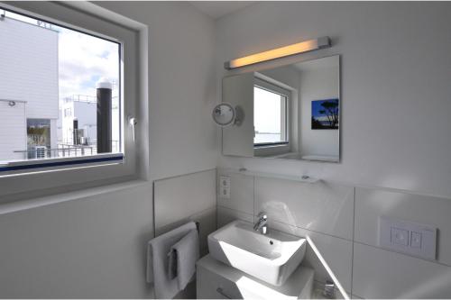 a white bathroom with a sink and a mirror at Schwimmendes Haus Hausboot in Olpenitz