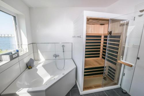 a white bathroom with a shower and a sink at Vogelvilla in Olpenitz