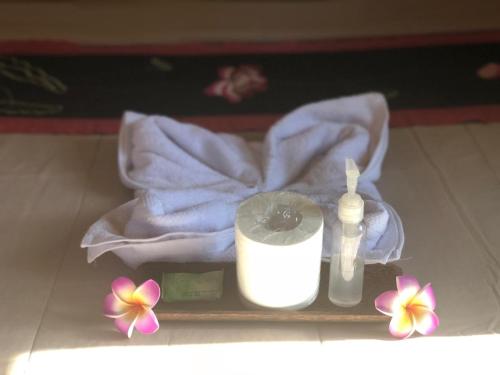 a bathroom with a towel and a candle and flowers at Depa House in Ubud