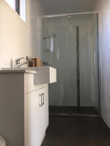 a white bathroom with a shower and a sink at Deniliquin Motel in Deniliquin