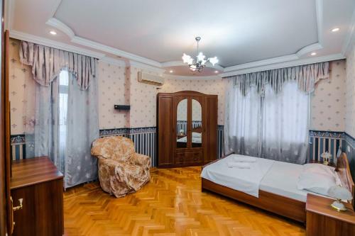 een slaapkamer met een bed en een stoel erin bij Mirza Fatali Akhundova 154 Apartment in Baku