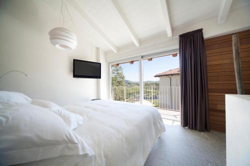 a bedroom with a white bed and a large window at Palas Cerequio in La Morra