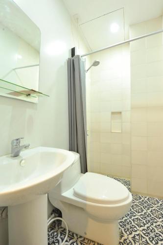 a white bathroom with a toilet and a sink at Down South Hostel in Cebu City