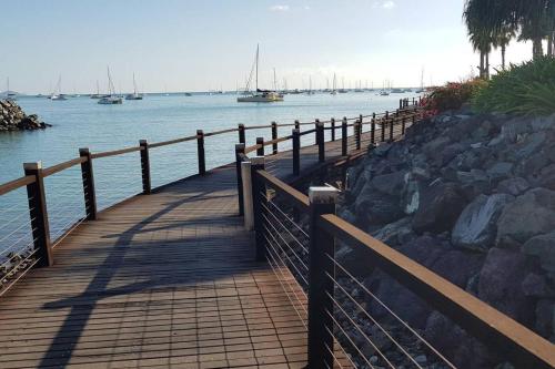 a wooden walkway next to the water with boats at DAYDREAMING Airlie Beach, Water views & only 200m to boardwalk. in Cannonvale