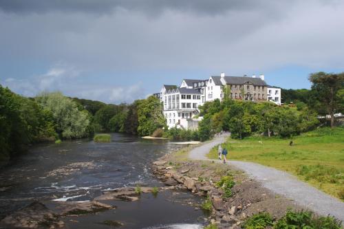 a person riding a bike next to a river at Falls Hotel & Spa in Ennistymon