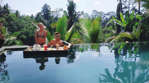 un homme et une femme assis à côté d'une piscine dans l'établissement Doni House & Villas, à Ubud