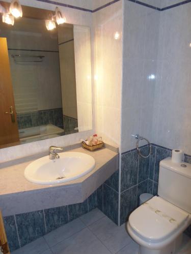 a bathroom with a sink and a toilet and a mirror at Hostal Stop in Cantalejo