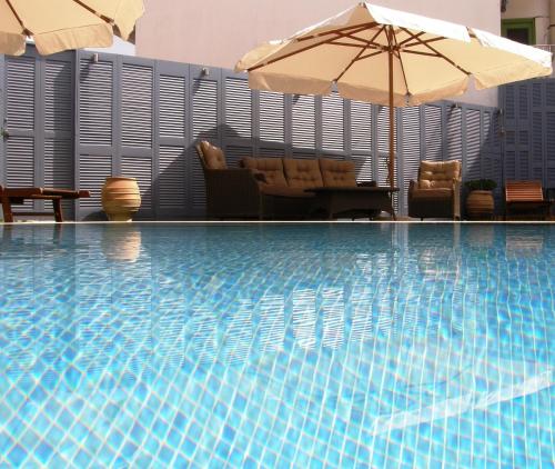 a large swimming pool with umbrellas and chairs at Anna Platanou Hotel in Parikia