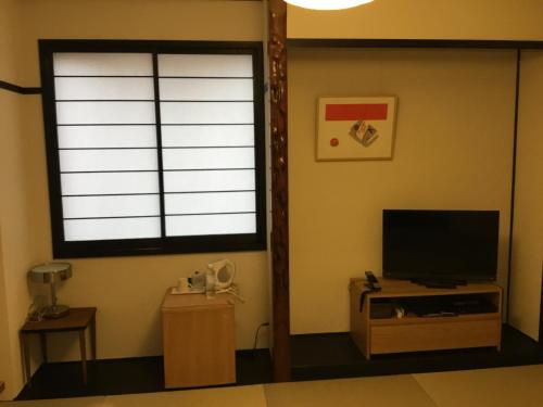 a living room with a large window and a television at Hotel Sun Road in Amakusa