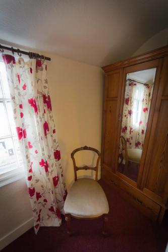 a room with a chair and a mirror and a window at The Angel Hotel in Helston