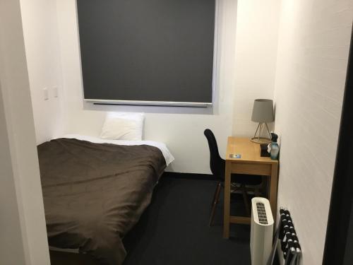 a room with a bed and a desk and a screen at Hotel Sun Road in Amakusa