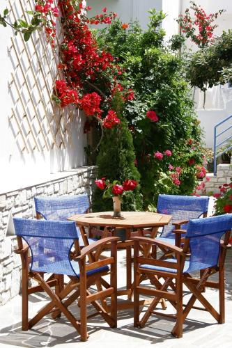 a wooden table and chairs with flowers on a patio at Anna Platanou Hotel in Parikia