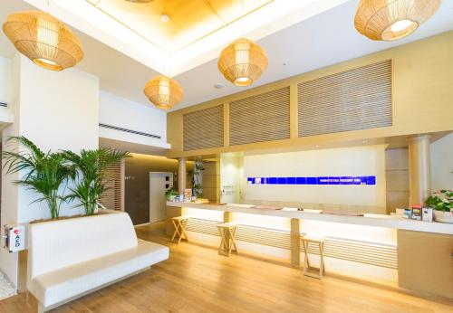 a lobby with a reception desk and a white bench at Nishitetsu Resort Inn Naha in Naha