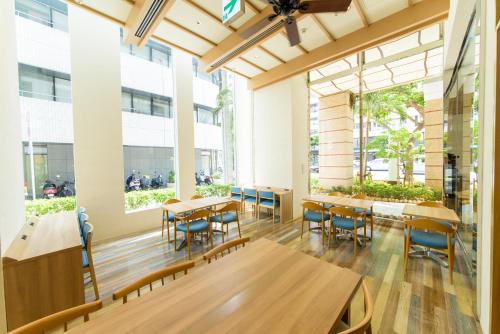 un comedor con mesas, sillas y ventanas en Nishitetsu Resort Inn Naha, en Naha