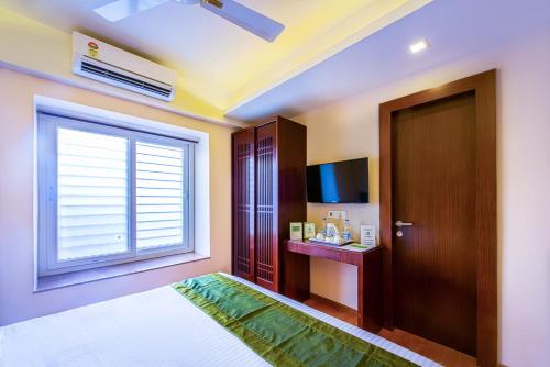 a bedroom with a bed and a window and a television at Treebo Vedanta, Metropolitan in Kolkata