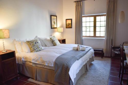 a bedroom with a bed with white sheets and a window at Wildekrans Country House in Botrivier