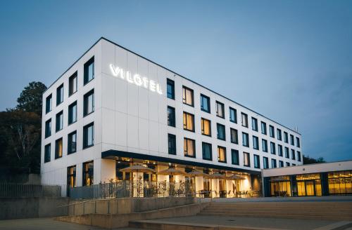 un gran edificio blanco con un cartel. en VILOTEL - Hotel & Restaurant, en Oberkochen