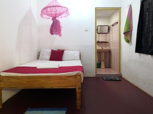 a small bedroom with a bed with a pink umbrella at Alass Ga for pets lovers in Trincomalee