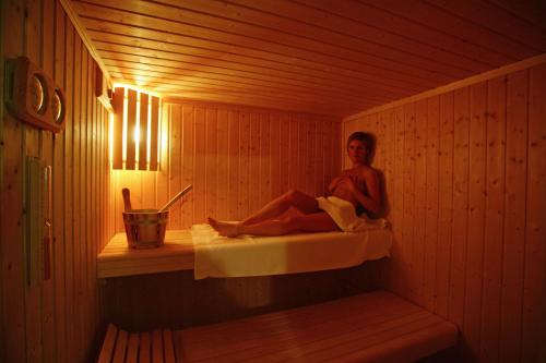 a woman is sitting in a sauna at Hotel Relais Valle Orientina in Pitigliano