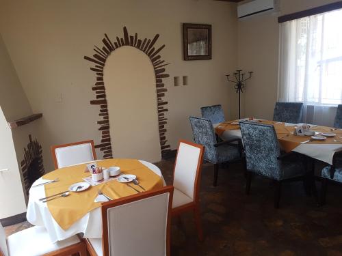 a dining room with two tables and a large arched doorway at Hotel Pension Steiner in Windhoek