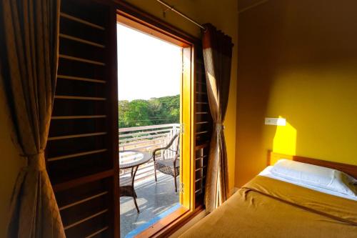 a bedroom with a window with a bed and a balcony at Osho Glimpse Mysore in Mysore