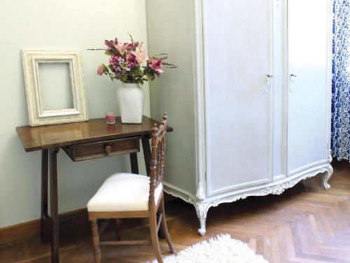 a room with a desk with a vase of flowers and a mirror at B&B Del Piazzo in Biella
