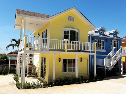 a yellow and blue house with a balcony at Bunny Hill Resort in Chon Buri