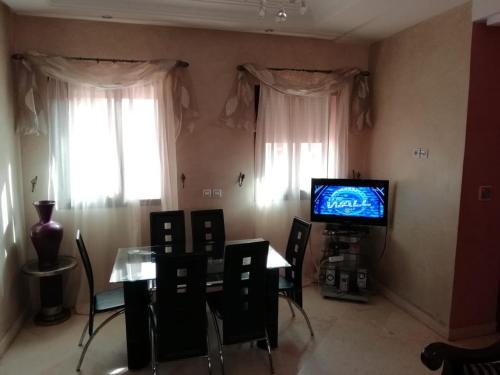 uma sala de estar com uma mesa de jantar e uma televisão em LINA APPARTEMENT em Marraquexe