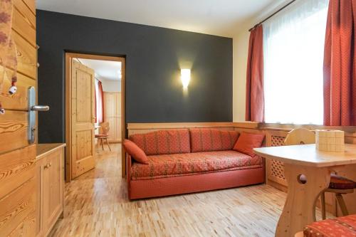 a living room with a red couch and a table at Berggasthof Locanda Alpina Dorfner in Montagna