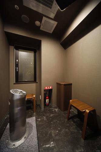 a room with a trash can and benches and a window at Dormy Inn Premium Osaka Kitahama in Osaka