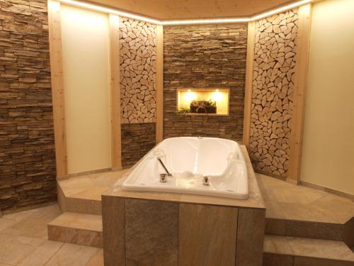 a bath tub in a bathroom with a stone wall at Das Waldhotel - Genuss & Wellness am Notschreipass in Todtnau