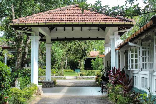 a white pergola with a bench under it at Plantation Villa in Kalutara
