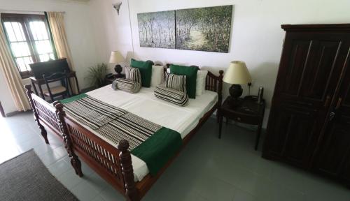 a bedroom with a bed with green and white pillows at Plantation Villa in Kalutara