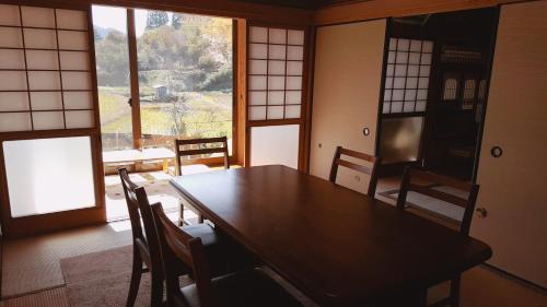 a dining room with a table and chairs and a window at Cocochi House in Yufuin