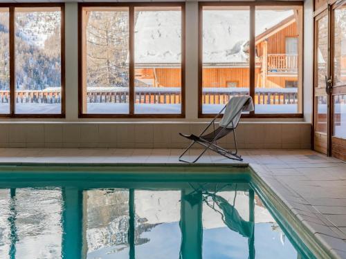 une chaise assise à côté d'une piscine dans une maison dans l'établissement SUNWEB Les Balcons de Bois Méan, aux Orres