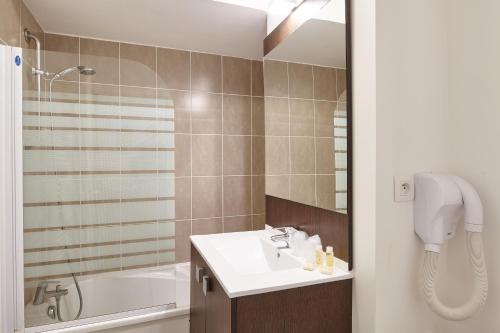 a bathroom with a sink and a bath tub at Résidence Vacances Bleues Les Jardins d'Arvor in Bénodet
