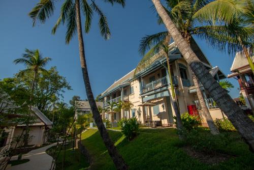 a house with palm trees in front of it at Le Bel Air Resort Luang Prabang in Luang Prabang