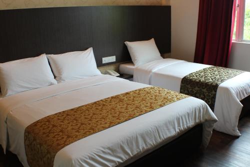 a hotel room with two beds and a window at Hotel Rosmerah in Ayer Keroh
