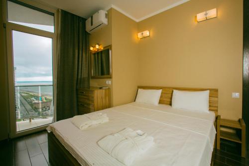 a bedroom with a large bed with a large window at Panorama Sea Tower in Batumi