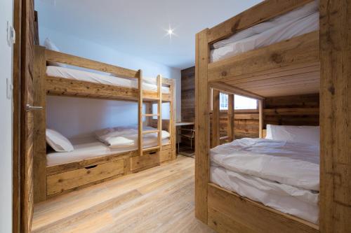 two bunk beds in a room with wooden walls at La Cordée 4 - Spa Access - Mer de Glace complex in Nendaz