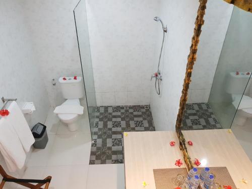 a bathroom with a toilet and a glass shower at Palm Bamboo Hotel in Nusa Dua