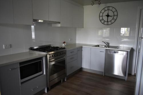 a kitchen with stainless steel appliances and a clock on the wall at Sussex Palms Holiday Park in Sussex inlet
