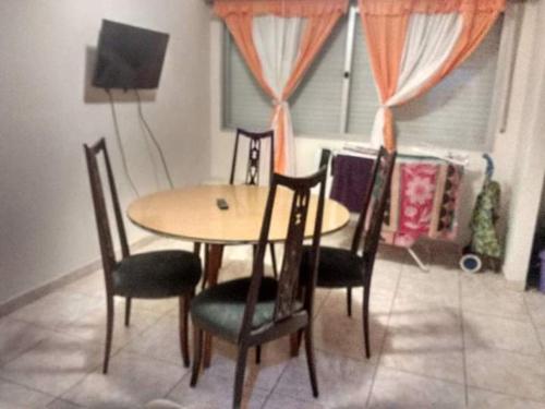 a dining room table with four chairs and a television at el cabo frente al mar in Mar del Plata