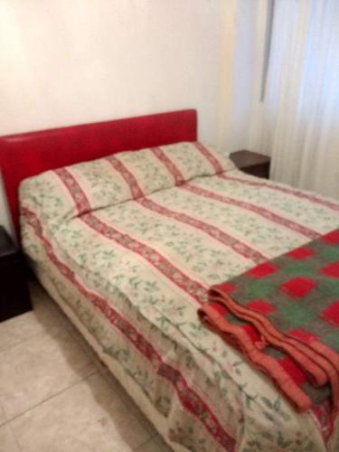 Una cama con una cabecera roja con un edredón. en el cabo frente al mar en Mar del Plata