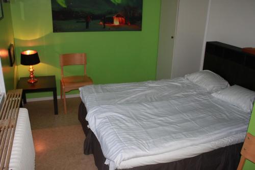 a bedroom with a bed and a chair and a lamp at Abisko net Hostel & Huskies in Abisko