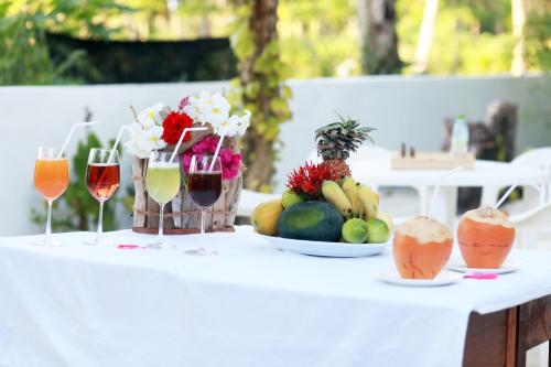 una mesa blanca con fruta y copas de vino en Alesara Guest House, en Thoddoo