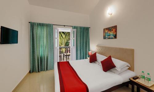 um quarto com uma cama branca e almofadas vermelhas em Santiago Beach Resort em Baga